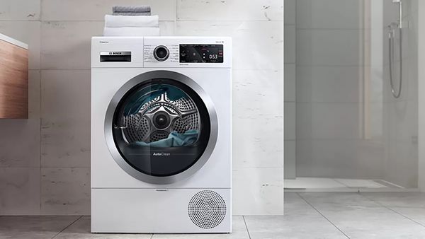 Eine freistehende Waschmaschine in einem Badezimmer, auf der sich ein paar gestapelte Handtücher befinden.