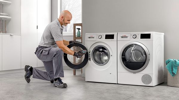 Un técnico reparando una lavadora en un cuidado cuarto de lavado.
