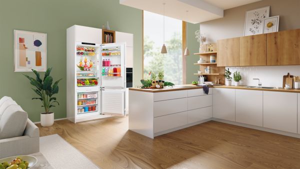 Uma cozinha apresenta um frigorífico/congelador bem abastecido com portas abertas.
