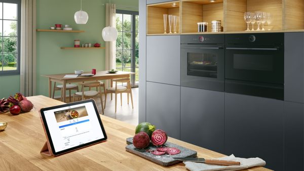 Een iPad op een kookeiland, met een recept op het scherm, met op de achtergrond ingebouwde ovens.