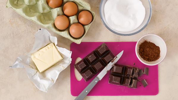  Draufsicht auf einen Karton Eier, Butter und andere Backzutaten. 