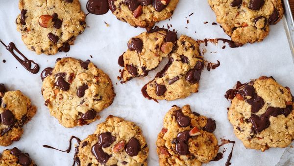 Chocolate Chip Cookies und Spuren geschmolzener Schokolade auf Backpapier.