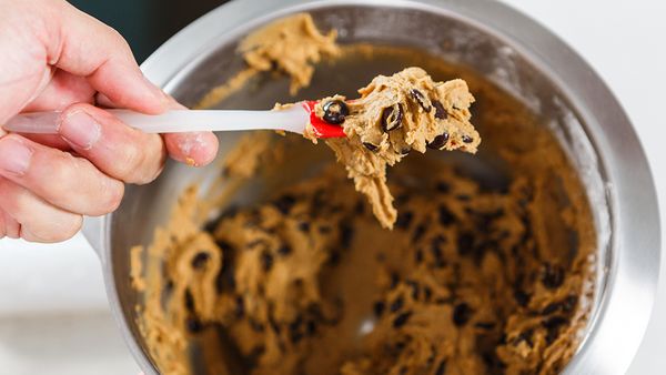 Draufsicht auf einen Teig für Chocolate Chip Cookies in einer Schüssel und auf einen Pfannenwender.