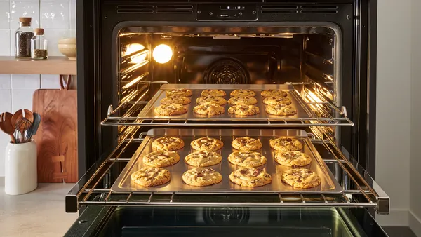 Two racks in an oven are extended to reveal trays of cookies.