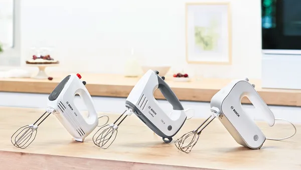 Three Bosch hand mixers lined up on kitchen counter.