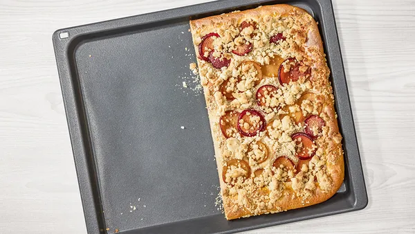 Half a crumble in a non-stick baking tray with no food residues on the empty side.