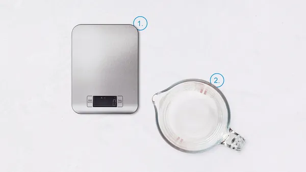 A digital kitchen scale and a glass measuring jug numbered 1 and 2.