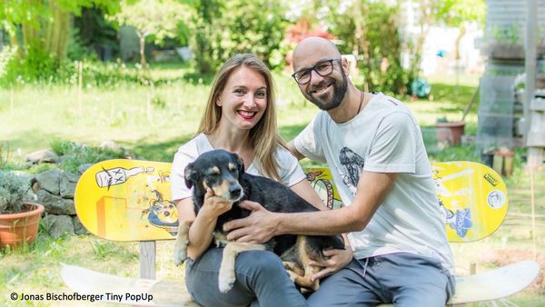 Felicia Rief und Jonas Bischofberger sitzen mit ihrem Hund auf einer Bank im Garten.