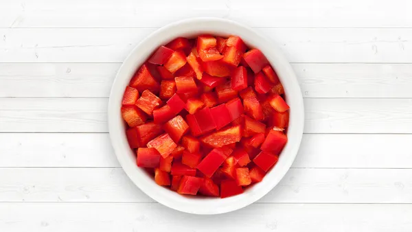 A white bowl of chopped red pepper.