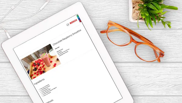 A view from above of a recipe on tablet, spectacles and a cactus.