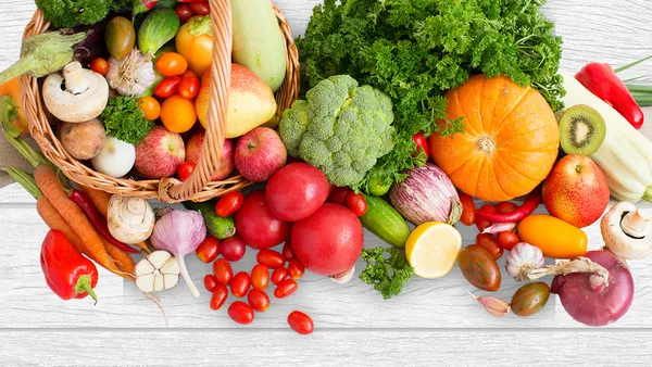 A basket of fresh fruit and vegetables with more surrounding it.