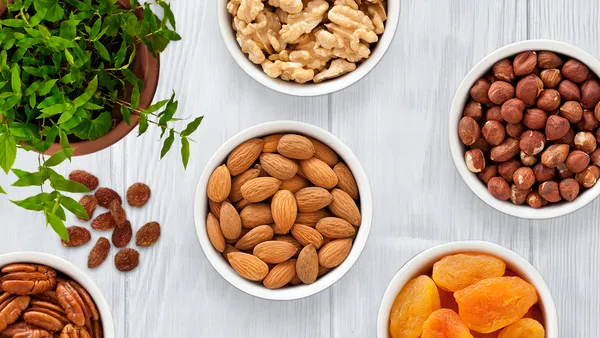 Little bowls of nuts and dried fruit with a potted herb plant.