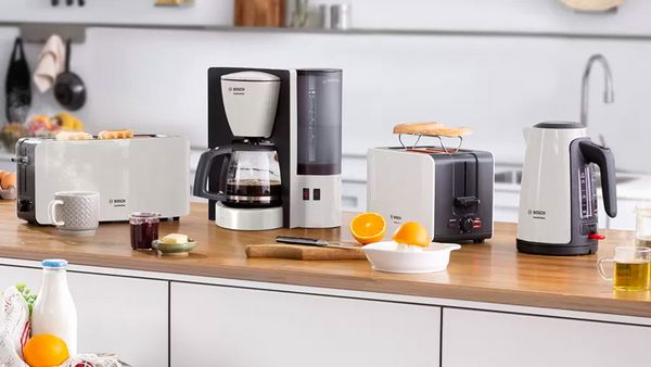 Ein Set aus Toaster, Kaffeemaschine und Wasserkocher in Schwarz und Weiß auf einer Holzarbeitsplatte.