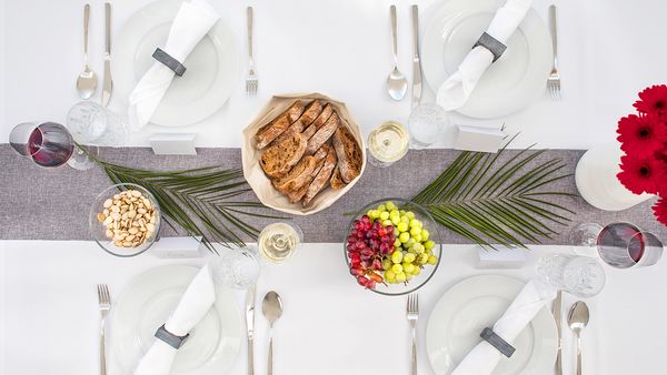 Draufsicht auf einen Tisch, der für das Abendessen eingedeckt und mit Blumen und Palmblättern dekoriert ist.