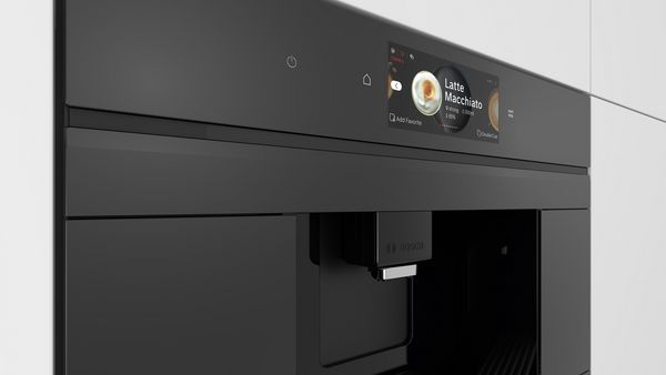 Personne utilisant un smartphone pour faire fonctionner une machine à café Bosch dans une cuisine moderne.