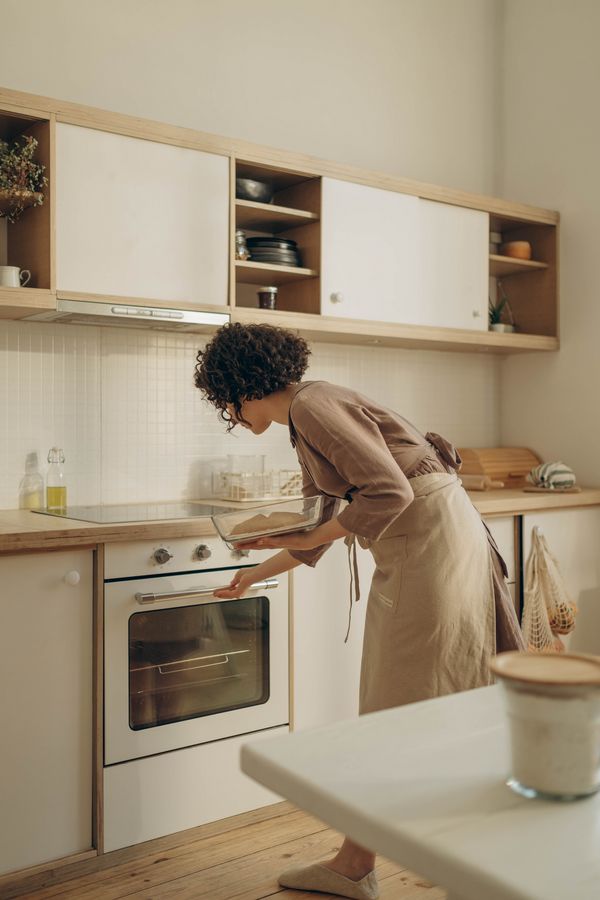 młoda kobieta w nowoczesnej kuchni, wstawia potrawę do piekarnika