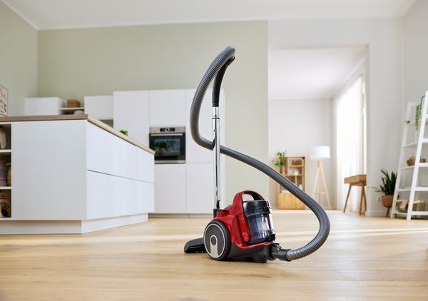 Aspirapolvere Bosch a traino su pavimento in legno, con cucina luminosa sullo sfondo