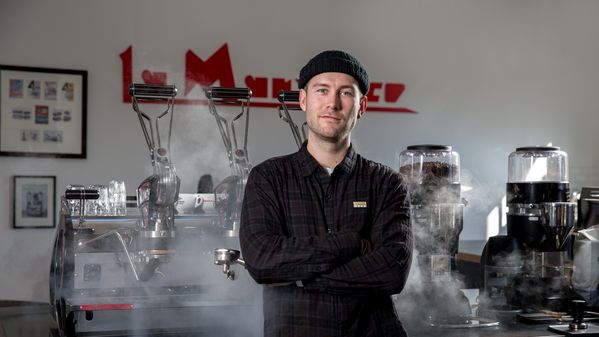 Portrait of Erik Martin standing in front of a La Marzocco coffee machine