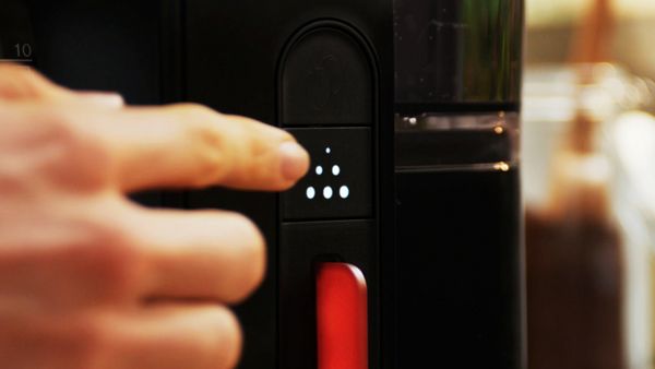 Close-up of descaling function button on coffee maker.