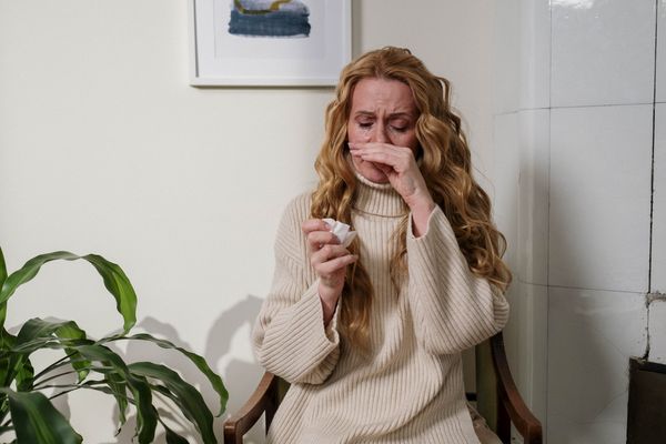 Kobieta mająca alergię wyciera nos chusteczką 