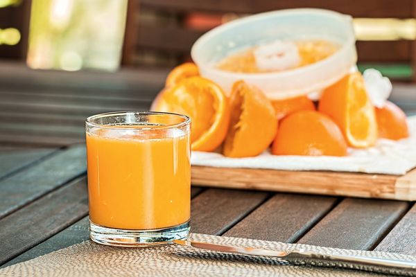 Szklanka z sokiem pomarańczowym z sokowirówki stoi na stole