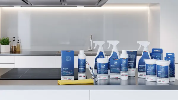 A selection of Bosch cleaning products on a white counter with a built-in oven in the background.