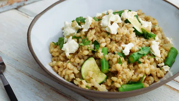 Barley risotto with green beans and feta in a white bowl. 