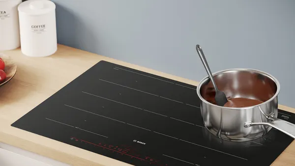 A stainless steel cooking pot with melting chocolate on an electric cooktop.