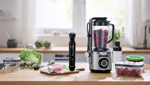 VitaPower Series 8 blender punjen bobičastim voćem na radnoj površini. Pored njega komad odreska u vrećici za sous vide.