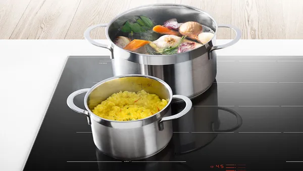 Two partially filled pots on a ceramic cooktop.