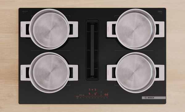 Vue de dessus de quatre casseroles rondes en acier inoxydable disposées sur les quatre zones de cuisson.