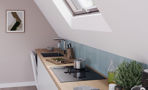 Ъглова перспектива на кухненско оформление под скосен покрив с плот Bosch с интегриран вентилиран модул.