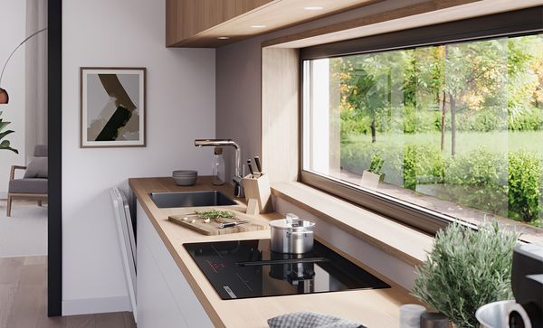 Ъглова перспектива на кухненско оформление под прозорец с плот Bosch с вграден модул за вентилация.