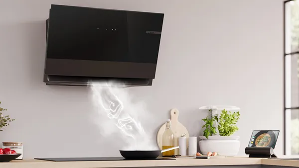 A black range hood captures the exhaust from a pan, and the steam takes on a dynamic shape in form of a fist-bump.