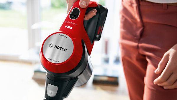 Bližnji posnetek roke, ki drži sesalnik, in upravljalnih elementov sesalnika Bosch Unlimited 7 ProAnimal.