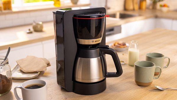 MyMoment coffee maker on kitchen top next to coffee cups.