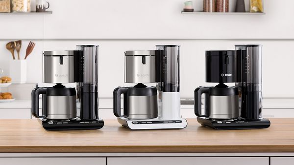 Drei Bosch Styline Filterkaffeemaschinen in Edelstahl, Weiß und Schwarz stehen nebeneinander.