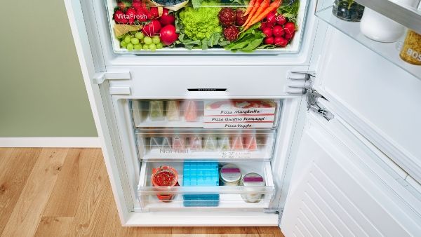 Freezer door open showing inside contents with no ice buildup
