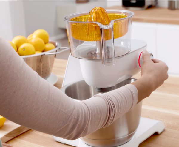 Eine Person presst frische Limetten mit einer Bosch Küchenmaschine mit Entsafter aus, um Saft herzustellen.