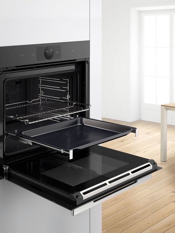 Forno da incasso Bosch aperto con teglia e griglia estratte, in una cucina luminosa