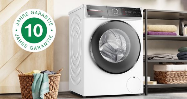 Integrierte Bosch Waschmaschine mit zusammengelegter Wäsche darauf. Das Symbol für die 10-Jahres-Garantie auf der linken Seite steht für die kostenlose Garantieverlängerung auf den Motor.