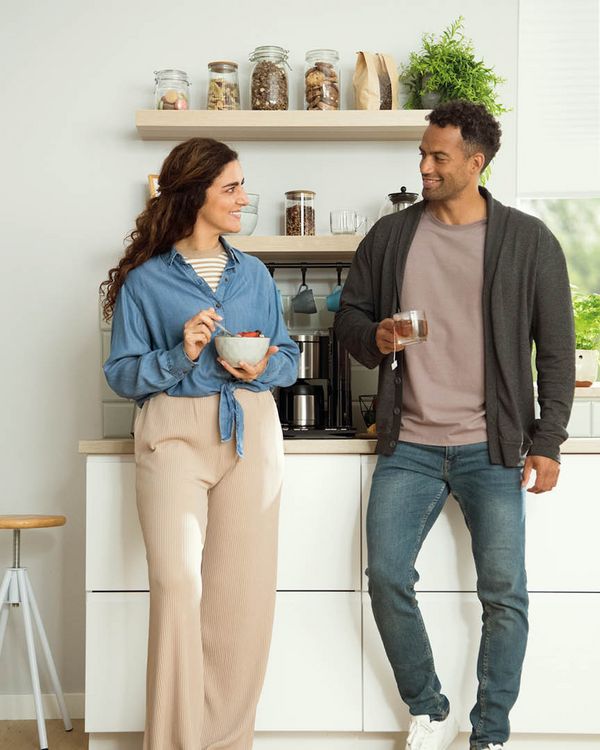 En kvinna och en man står i ett kök och dricker te.