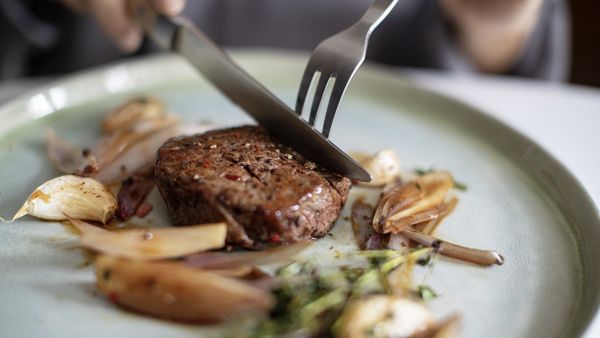 Ein Steak mit Röstaromen liegt auf einem Teller mit Gemüse.