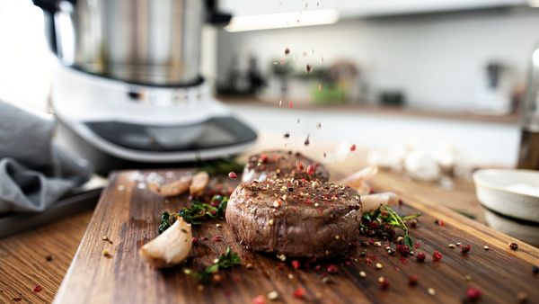Ein Stück Fleisch, das im Bosch Cookit gebraten wurde, liegt auf einem Holzbrett.