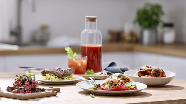 O selecţie de preparate, inclusiv cârnaţi, salată, chiftele de falafel şi cuşcuş lângă o sticlă şi un pahar cu suc de fructe.