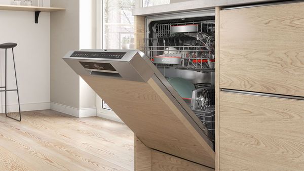 A semi-integrated dishwasher built-in to wooden cabinets in a modern kitchen.