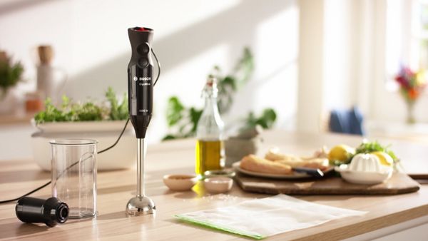 An ErgoMixx hand blender clustered with its accessories on a counter in a bright, white kitchen.
