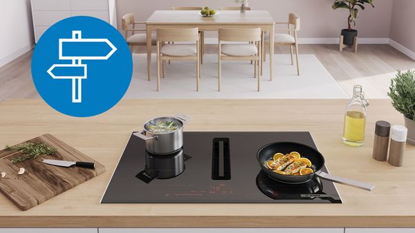 Guide d'achat Interactif pour les table de cuisson Bosch montrant deux casseroles chaudes sur une table de cuisson à induction avec hotte intégrée.