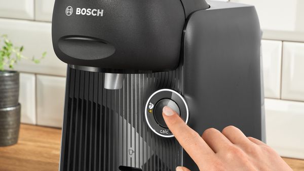 A person clicks on the start button of TASSIMO FINESSE coffee machine.