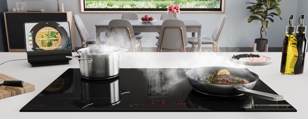 Moderná kuchyňa s kuchynskými spotrebičmi, jedálenský stôl, a veľké okno s výhľadom na zeleň. 